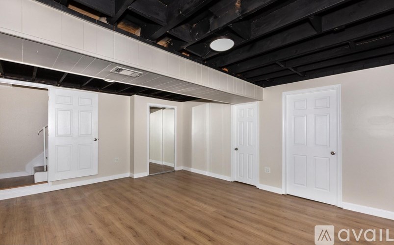 A spacious room with white doors and wooden flooring.