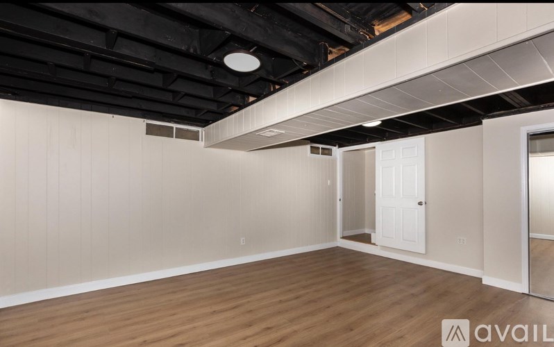 A spacious room with wooden flooring and white walls.