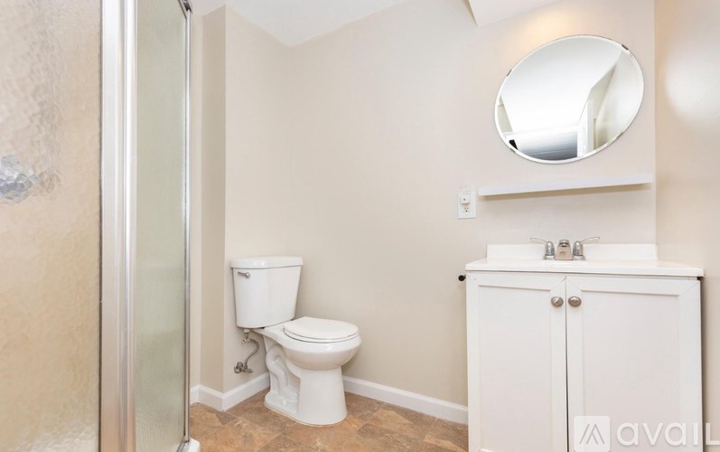 A bathroom with a toilet, sink and mirror.