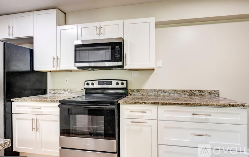 A kitchen with black appliances and white cabinets.