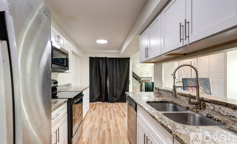 A modern kitchen with wooden floors and white cabinets.