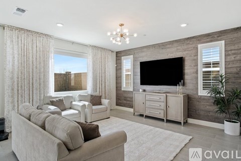 A living room with a grey couch and a television on the wall.