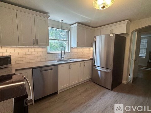 A kitchen with white cabinets and a stainless steel refrigerator.