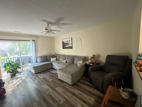 A living room with a grey couch and a ceiling fan.