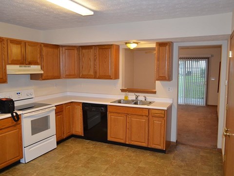 A kitchen with wooden cabinets and a black dishwasher.