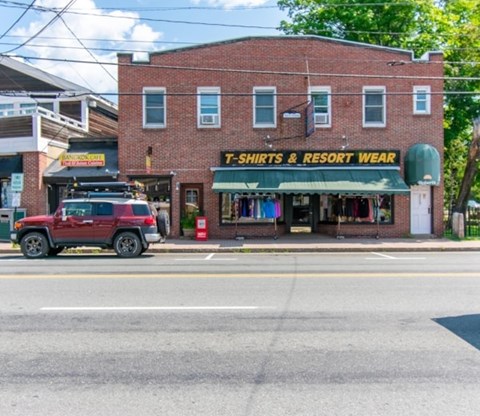 A red SUV is parked in front of a T-shirts and resort wear store.