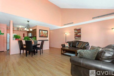 A living room with a brown leather couch and a dining table with chairs.
