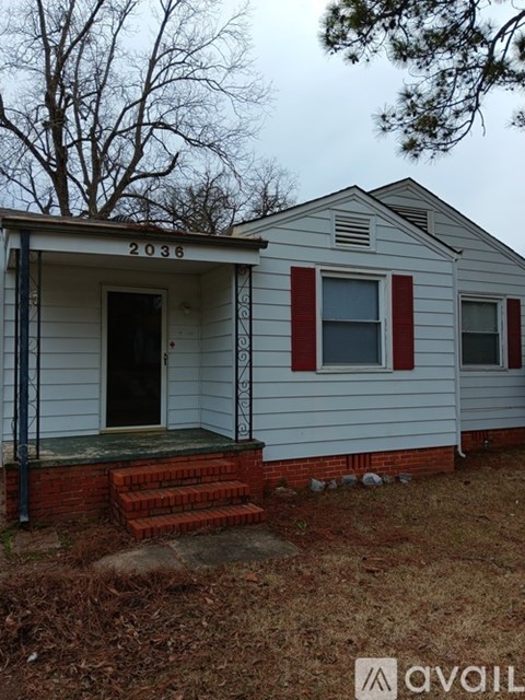 A white house with red trim and a black door numbered 2038.