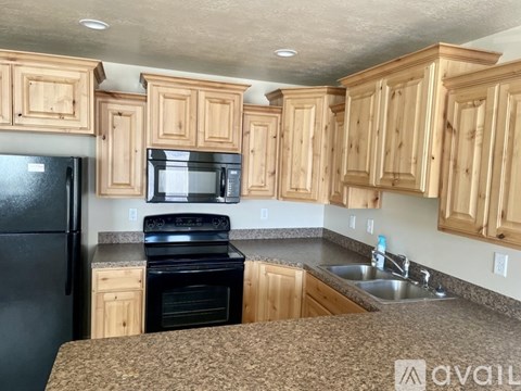 A kitchen with wooden cabinets and black appliances.