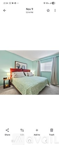 A bedroom with a bed, nightstand, and window.