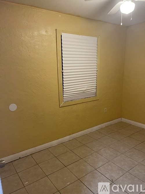 A room with a window covered by white blinds.