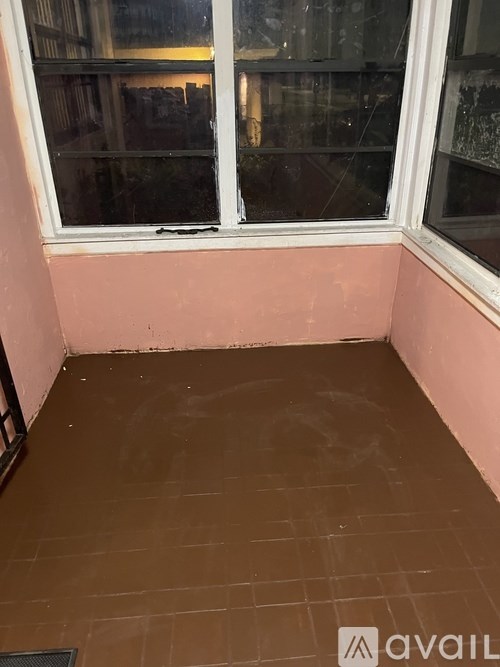 A room with a window and a brown floor.