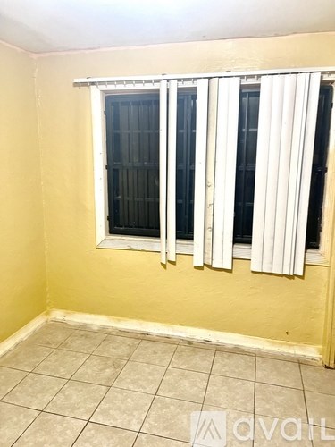 A room with a window covered by white curtains.