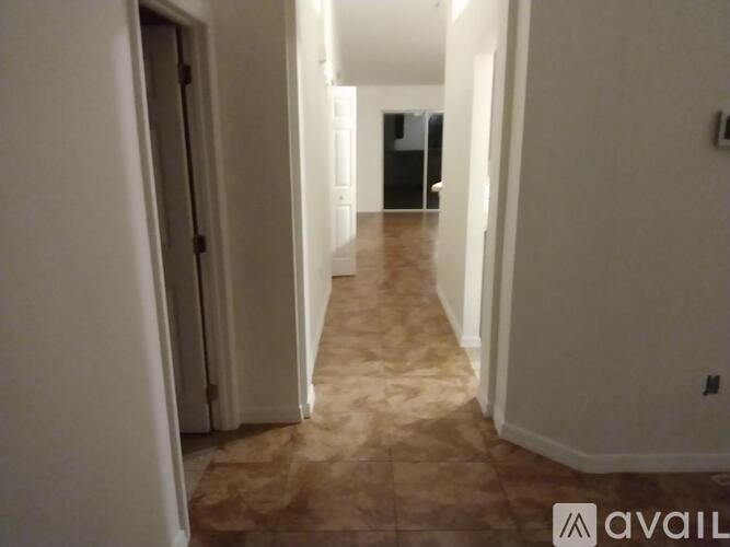 A long hallway with a brown carpet and white walls.