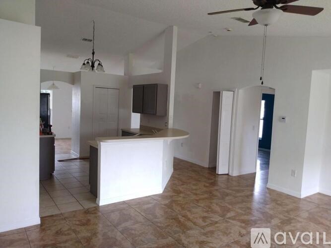 A spacious living room with a white kitchen island and a ceiling fan.