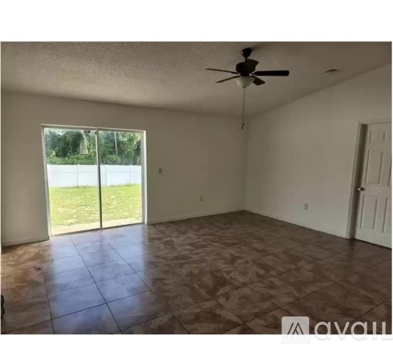 A room with a ceiling fan and sliding glass doors.
