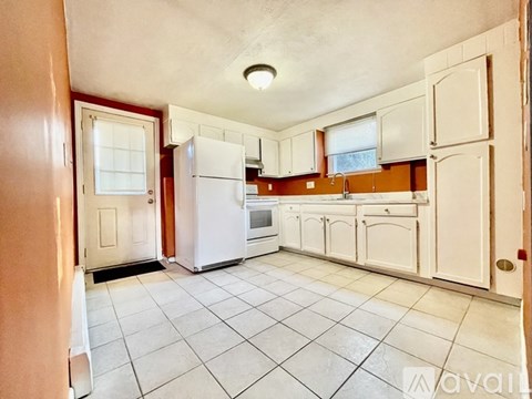 A kitchen with white cabinets and a white refrigerator.