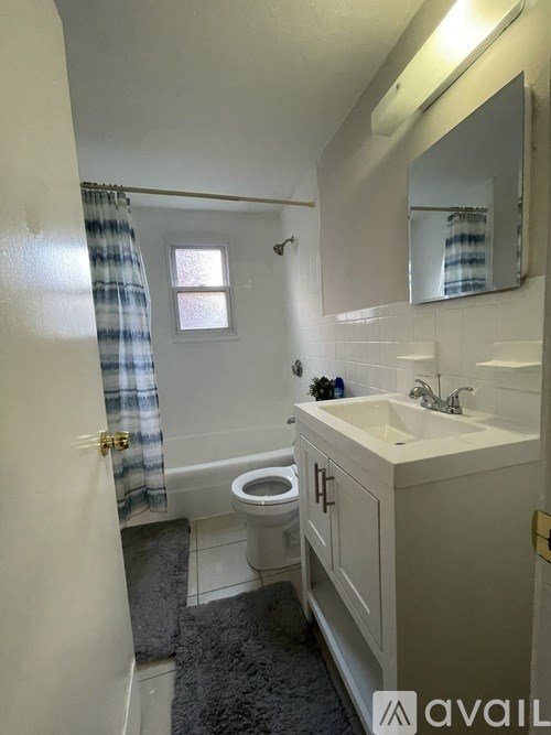 A bathroom with a toilet, sink, and mirror.