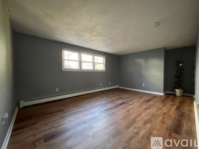 A room with wooden flooring and two windows.