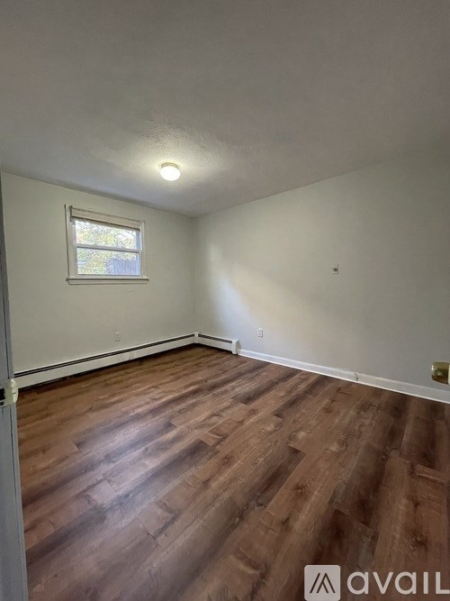 A room with wooden flooring and a window.