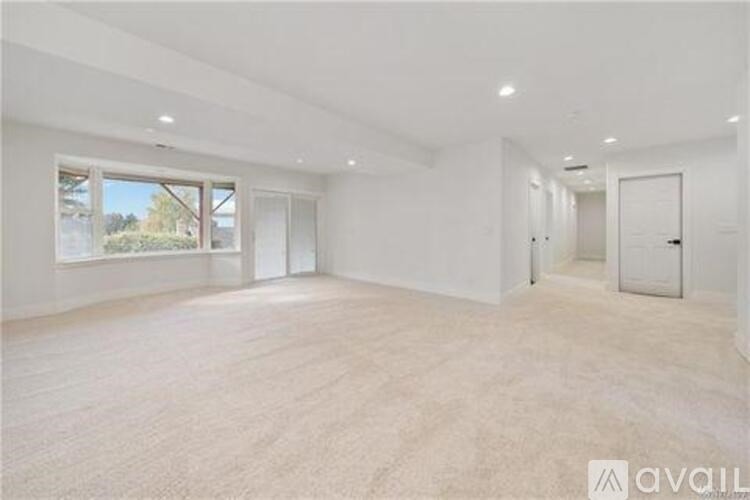 A spacious empty room with a large window and a door.