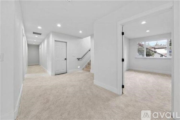 A spacious room with a staircase and a window overlooking a snowy landscape.