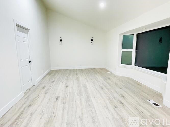 A room with wooden flooring and a window with a white frame.