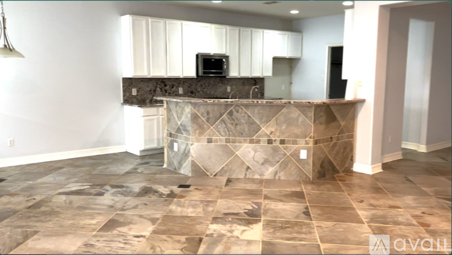A kitchen with a stone counter top and a microwave on it.