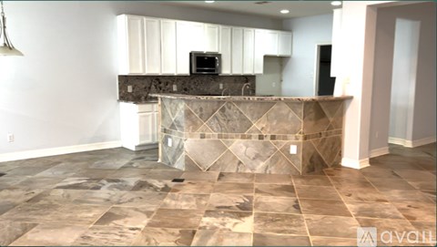 A kitchen with a stone counter top and a microwave on it.