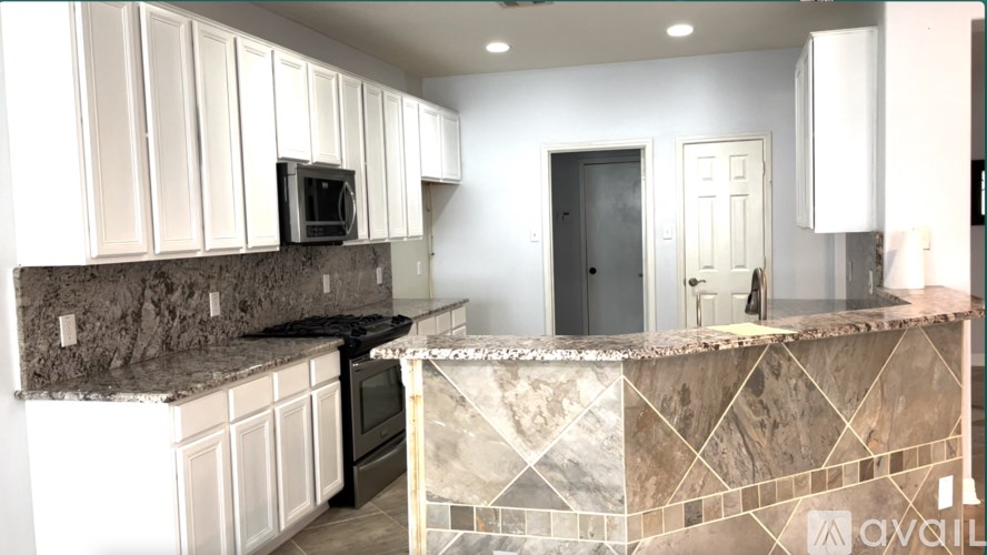 A kitchen with a marble countertop and white cabinets.