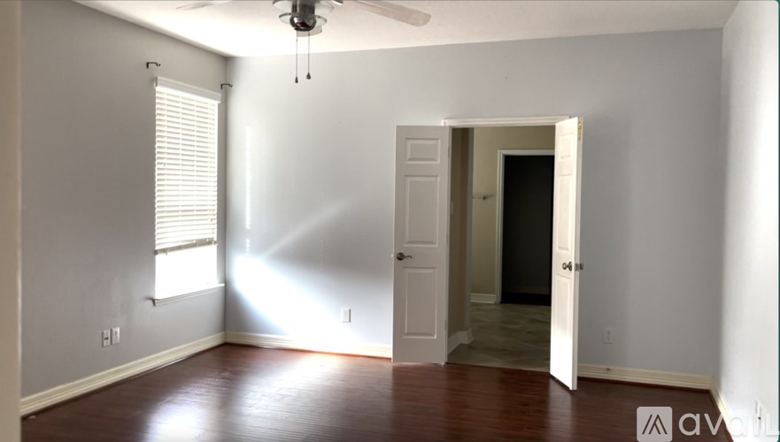 A room with a ceiling fan and a doorway leading to another room.