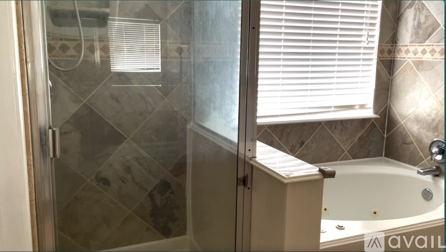 A bathroom with a glass shower door and a bathtub.