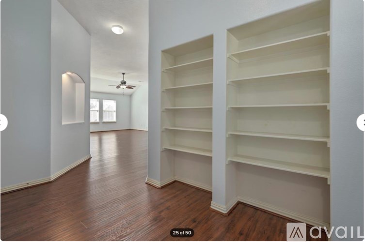 A room with wooden floors and white shelves.