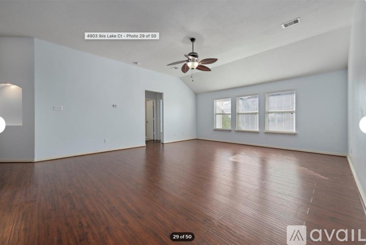 A spacious room with wood flooring and a ceiling fan.