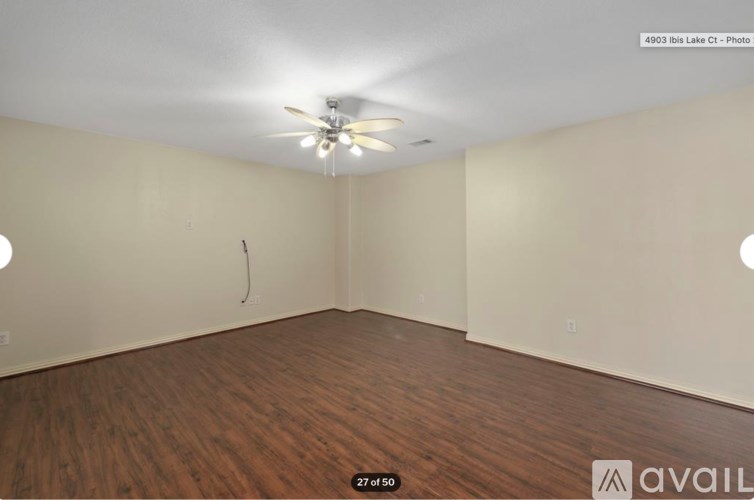 A room with a ceiling fan and wooden flooring.