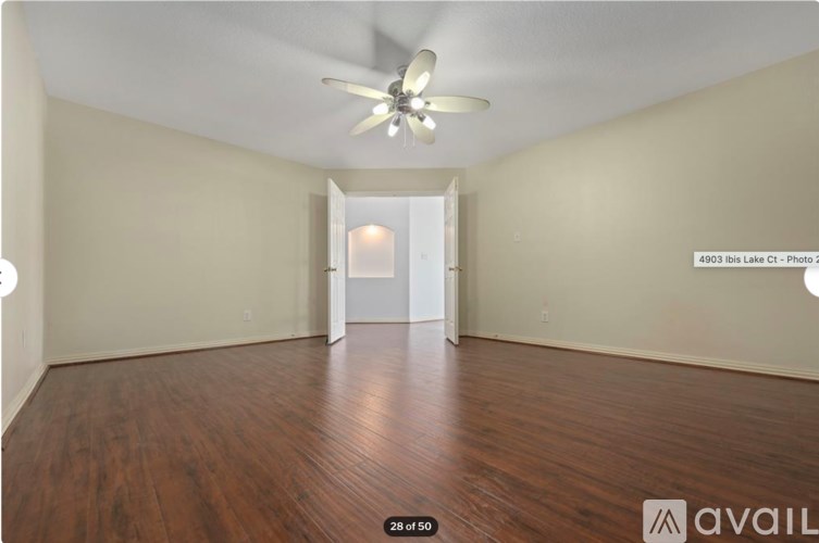 A room with a ceiling fan and wooden flooring.