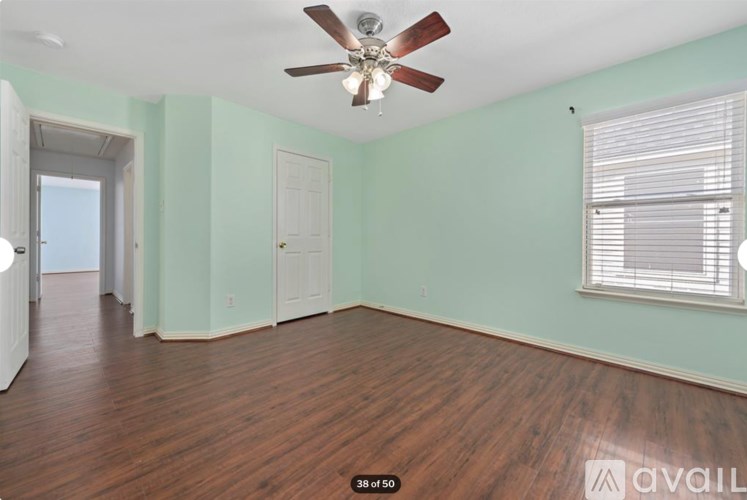 A room with a ceiling fan and wooden flooring.