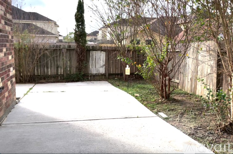 A backyard with a concrete patio and a wooden fence.