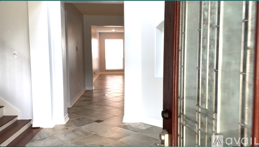 A hallway with a tiled floor and a staircase on the left side.
