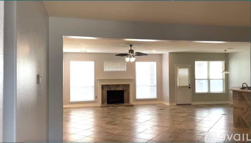 A spacious living room with a fireplace and a ceiling fan.