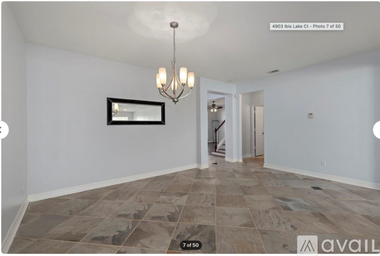 A spacious room with tiled flooring and a chandelier.
