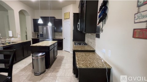 A kitchen with black cabinets and a granite countertop.