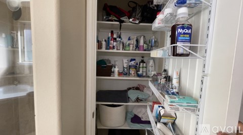 A bathroom with a white door open to a cluttered white shelf.