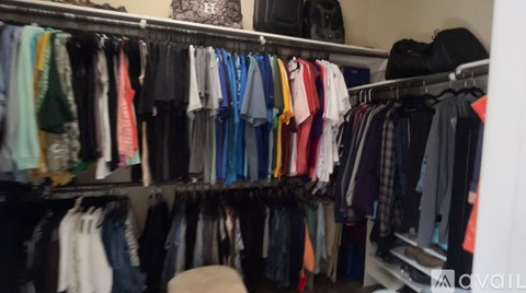 Clothes hanging on a rack in a closet.