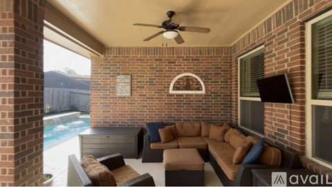 A patio with a couch, chairs, and a fan.
