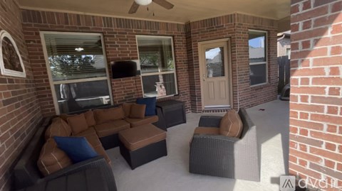 A patio with a couch, chairs, and a ceiling fan.
