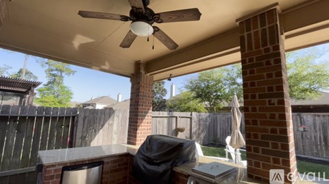 A patio with a ceiling fan and a table with a laptop on it.