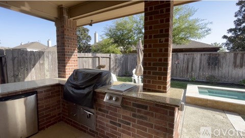 A patio with a grill and a pool in the backyard.