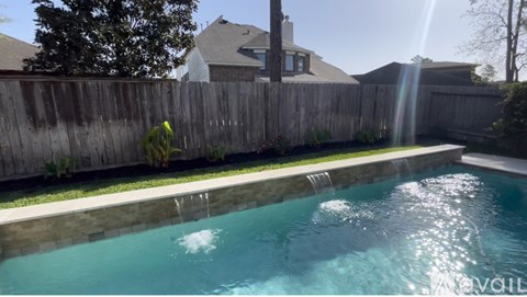 A pool with a wooden fence and a house in the background.