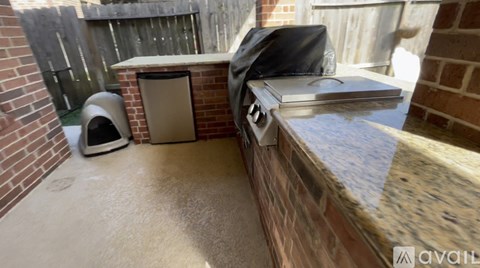 A backyard with a grill and a trash can.